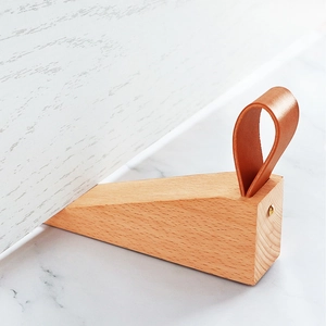 Nordic beech wood door stopper wedge with brown leather handle on marble surface