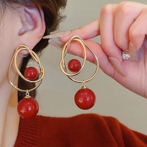 Gros plan de boucles d'oreilles double perle rouge avec maillons dorés sur un mannequin