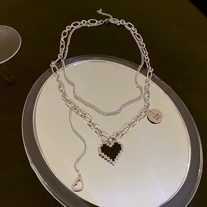 Vue macro du collier double rangée en acier inoxydable avec cœur pixel et médaillon gravé