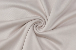 Macro shot of light beige knitted fabric texture with elegant pleated draping details