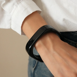 Close-up of minimalist black resin geometric bangle with glossy finish on a woman's wrist