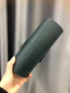 Detail of dark green leather makeup brush holder with stitch texture and buckle closure