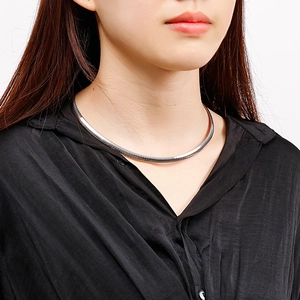 Close-up of a sleek silver stainless steel omega chain necklace worn by a model