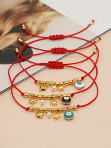 Detailed view of three handmade red braided friendship bracelets with evil eye charms