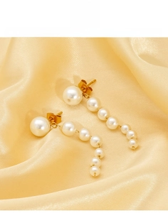 Detail of drop earrings with white pearls on champagne silk background in 18K gold finish
