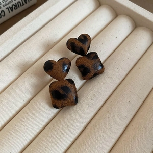 Macro view of vintage heart and square earrings with brown leopard print fabric texture