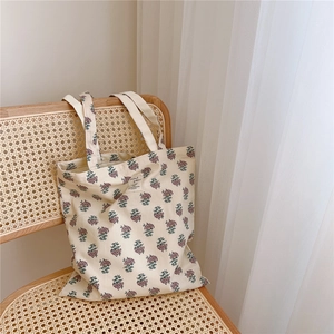 Floral canvas tote bag in vintage purple print resting on a rustic rattan chair