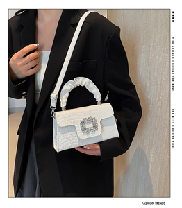 Detail shot of the crocodile-textured white handbag with a luxury crystal buckle detail