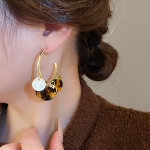 Close-up of leopard print dangle earrings with gold rings on model in brown knitwear