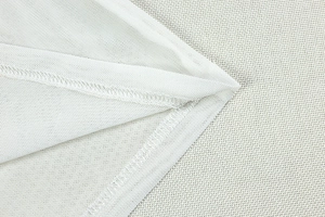 Gros plan sur la texture du tissu en maille blanche et les coutures de l'ourlet de la robe