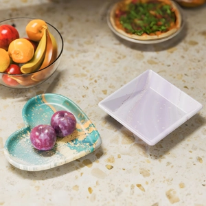 Detail shot of heart-shaped and square resin trays with gold marble patterns