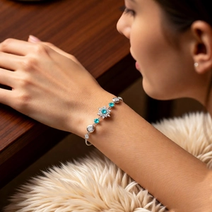 Close-up of a silver snowflake bracelet featuring a bright turquoise zircon on a model's wrist