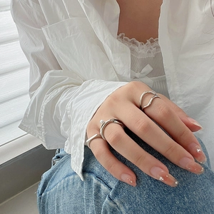 Close-up of three minimalist silver rings featuring a small pearl and wavy geometric bands