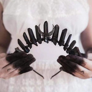 Close-up of gothic black crystal moon crown held by hands with celestial moon tattoos