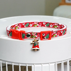 Detail of red Christmas pet collar with polka dots, festive charms and a jingle bell