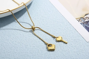 Detail der verstellbaren goldenen Schlangenkette mit Herzschloss und Schlüssel-Anhänger