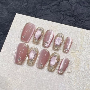 Handgefertigte rosa-goldene Cat-Eye-Nägel mit Goldfolie und Strassverzierungen