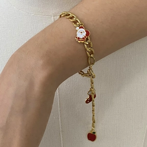 Detailed view of a gold chain bracelet with enamel Santa, sock, and apple charms