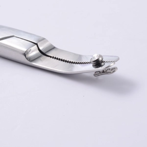 Macro shot of stainless steel piercing tool with serrated tip holding a clear rhinestone