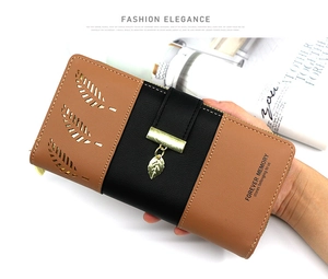 Detailed view of long patchwork wallet with hollow leaf design and gold leaf pendant