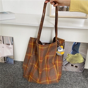 Detail of wool tote bag featuring vintage brown plaid pattern and a cute penguin charm