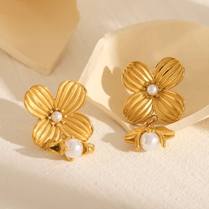18k gold plated stainless steel flower earrings with white pearls on a stone surface