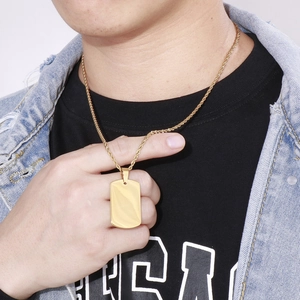 Détail d'un collier pour homme avec plaque rectangulaire dorée et chaîne torsadée