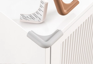 L-shaped silicone corner guards in white, grey, and beige shown on a furniture edge