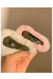 Detail showing the metal base and plush texture of white and pink hair clips
