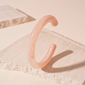 Detailed view of pink marble resin C-shaped open bangle with smooth acrylic texture