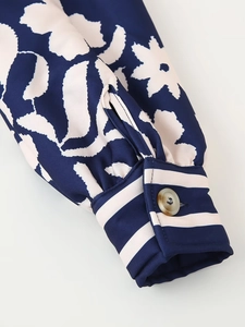 Dettaglio del polsino blu navy con stampa crema e bottone marrone sul cappotto