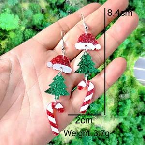 Macro detail of acrylic Christmas earrings with hat, tree and candy cane glitter charms