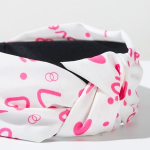 Detail of white knotted headband with pink heart prints and LOVE lettering pattern
