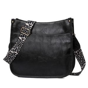 Close-up of black faux leather tote bag with leopard print wide strap and gold hardware