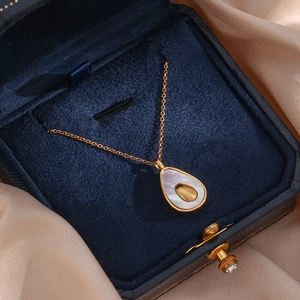Elegant gold pear-shaped avocado pendant with white shell inlay in a velvet jewelry box