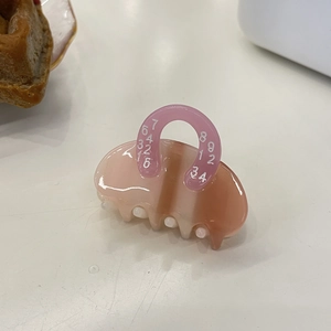 Macro detail of a pink and brown gradient acetate hair claw with white numeric patterns