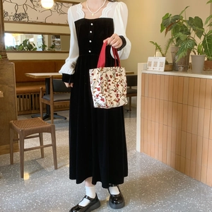 Detail of vintage floral canvas tote bag paired with a black velvet midi dress in a cafe