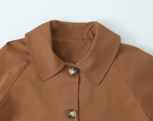 Detail of brown trench coat lapel featuring tortoiseshell button and premium stitching