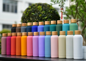 Detailed row of matte stainless steel thermal bottles with natural bamboo lids in various colors