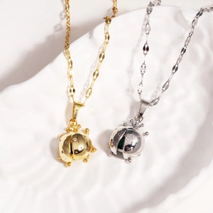 Detailed macro view of gold and silver ladybug necklaces with crystals on a textured plate