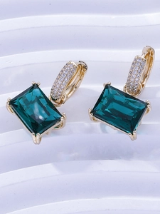 Macro detail of emerald green rectangle zircon earrings with gold micro-pave setting
