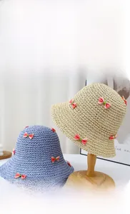 Détail d'un chapeau de paille tissé main avec texture ajourée et petit nœud rose décoratif
