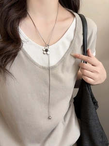 Detail of silver flower pendant necklace with elegant vertical metal tassel chain