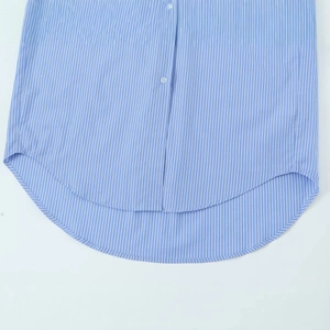 Relaxed blue and white vertical striped shirt featuring a high-low curved hem design