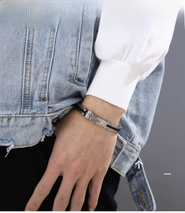 Detail of men's matte steel bracelet with black carbon fiber inlay and rivet accents