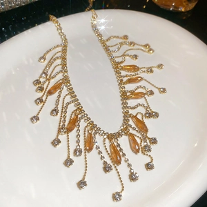Detailed close-up of champagne gold crystal fringe necklace on white porcelain