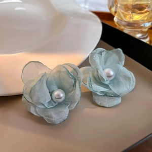 Detailed macro view of mint green organza flower earrings featuring white pearl centers