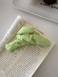 Detail of mint green ruched fabric hair claw clip on fashion magazine backdrop