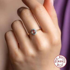 Detail of S925 silver ring with oval pink opal and blue enamel on a model's finger