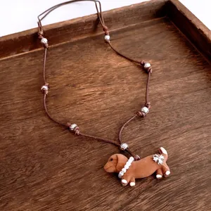 Brown woven leather necklace with a flocked dachshund puppy pendant and pearl detail